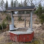 Puits en bois rouge avec son toit à l'orée d'un bois